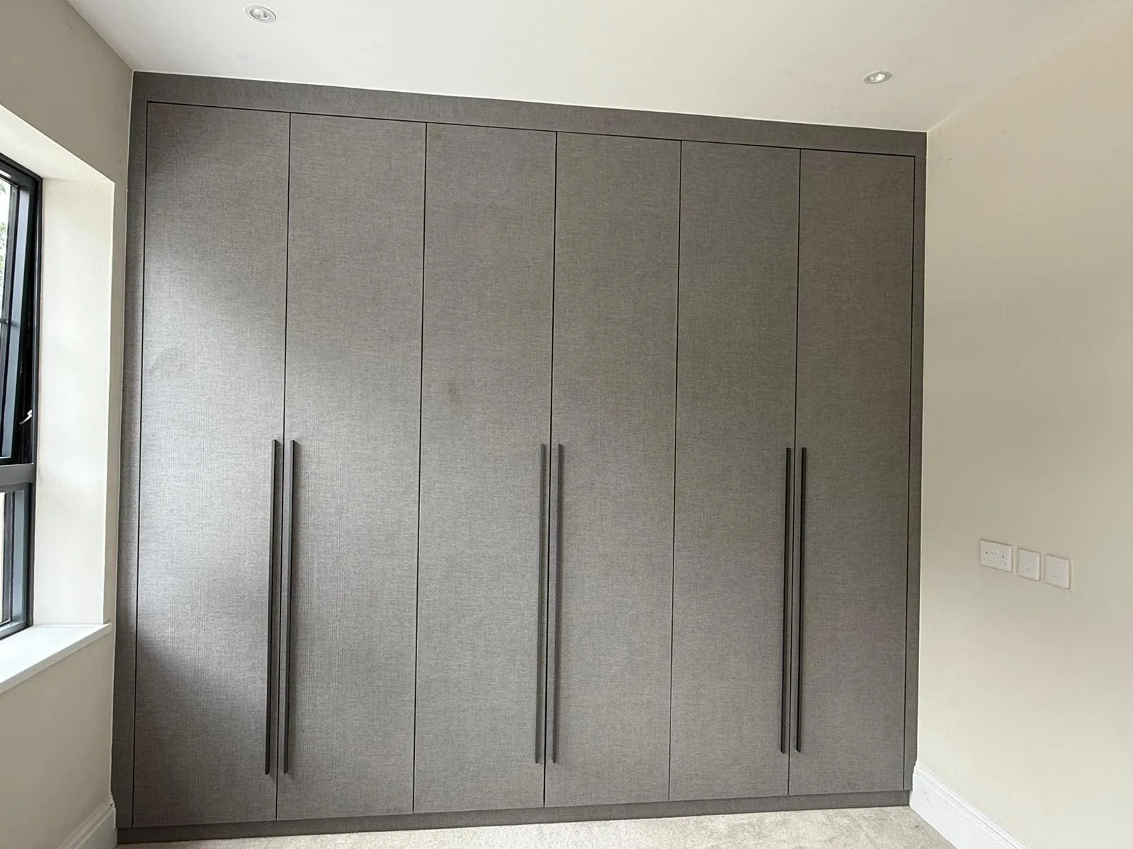 Floor-to-ceiling fitted wardrobes with one bay open